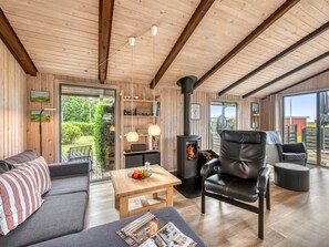 A cozy cabin interior with a sofa, a table with fruit, a leather chair, and a wood-burning stove. - "Clea" - 250m to the fjord by Interhome (Skjern)