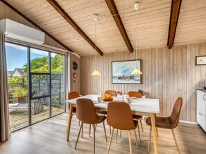 Un comedor con techo de madera, un ventanal grande y una mesa con sillas.
