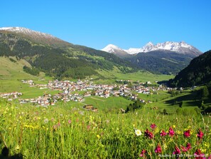 Eine Stadt liegt eingebettet in einem Tal, mit Bergen im Hintergrund.