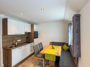 Eine kompakte Küche mit weißen Schränken, einer Holz Arbeitsplatte und einem eingebauten Backofen.