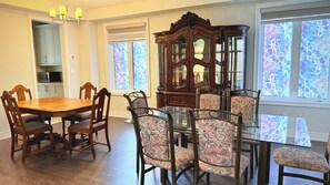 A dining room with a wooden table and chairs, a glass-top dining table, and a wooden cabinet with glass doors. - Sleeps 16 and more | Bedrooms with ensuite washrooms (Springwater)