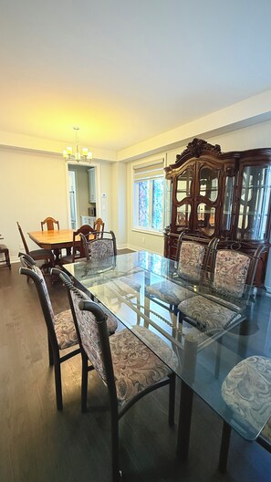 A dining room with a glass-top table, wooden chairs, and a large wooden cabinet with glass doors. - Sleeps 16 and more | Bedrooms with ensuite washrooms (Springwater)