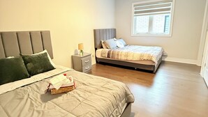 Quarto com duas camas, mesa de cabeceira, abajur e janela com persianas.