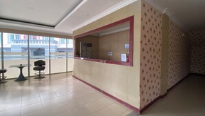 A reception area with a counter, chairs, and a view of a building outside. - Hotel O near Nagoya Hill Mall formerly J (Batam)