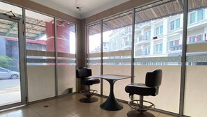 A room with two chairs and a table, large windows with a view of buildings, and a tiled floor. - Hotel O near Nagoya Hill Mall formerly J (Batam)