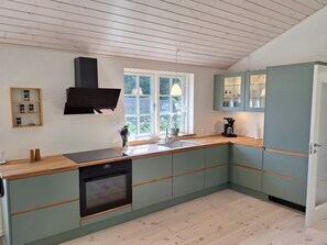 Eine moderne Küche mit Backofen, Spüle und einem Fenster mit Blick auf Grünflächen.
