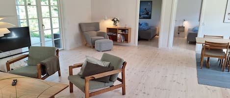 A spacious living area with a television, seating, and a bookshelf.