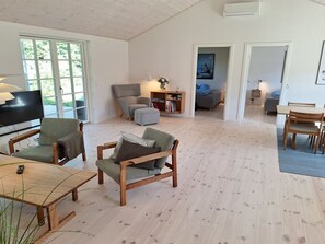 Ein geräumiger Wohnbereich mit Fernseher, Sitzgelegenheiten und einem Bücherregal.
