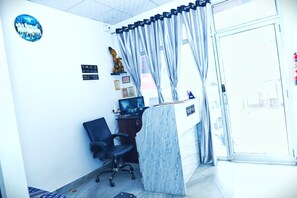 A reception area with a desk, chair, and curtains. - Hotel Relax (Jaipur)