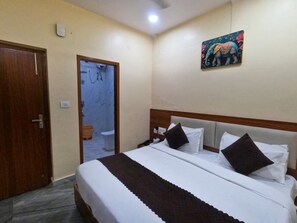 A hotel room with a bed, bedside table, and a painting on the wall. - Hotel Relax (Jaipur)