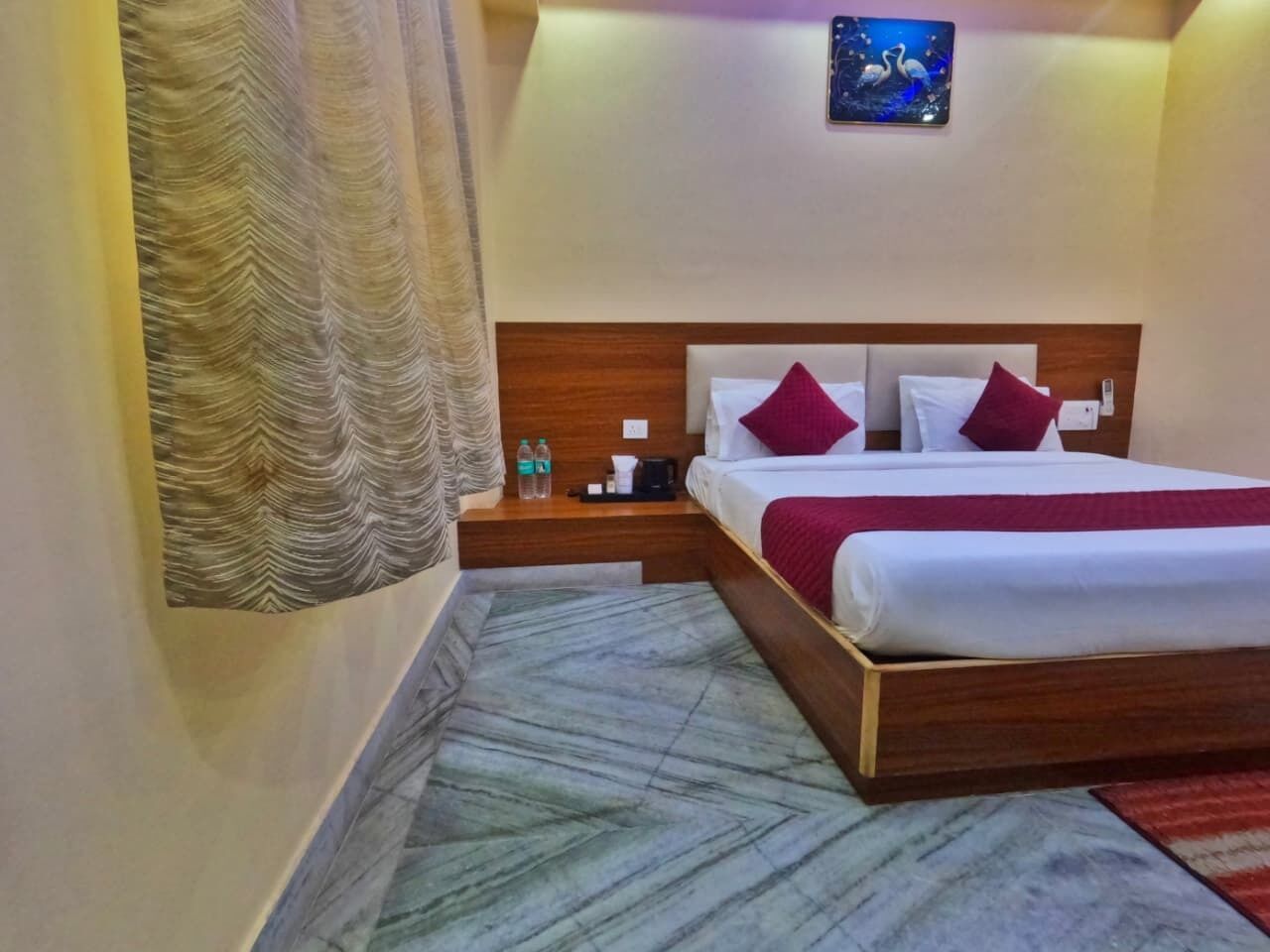 A hotel room with a bed, nightstands, a painting, and a marble-patterned rug.