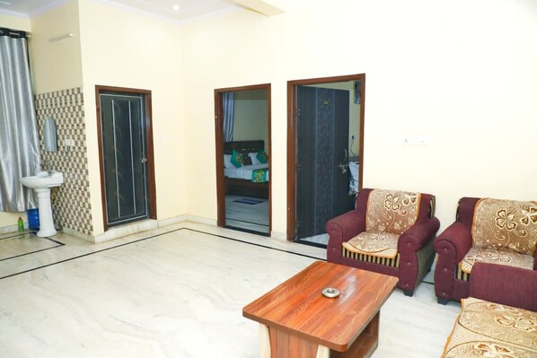 A living room with a sofa set, a coffee table, and a bathroom with a sink and toilet. - Hotel Relax (Jaipur)