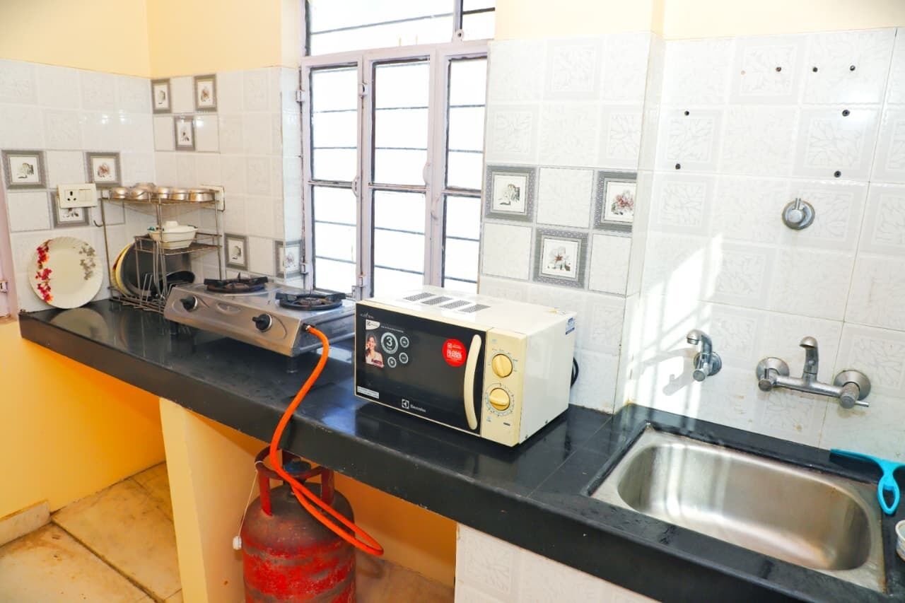 Una cocina con estufa a gas, tostadora, pileta y ventana.