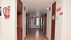 A hallway with wooden doors, a fire extinguisher, and signs on the walls.
