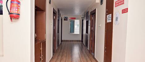 Un pasillo con puertas de madera, un extintor y letreros en las paredes.