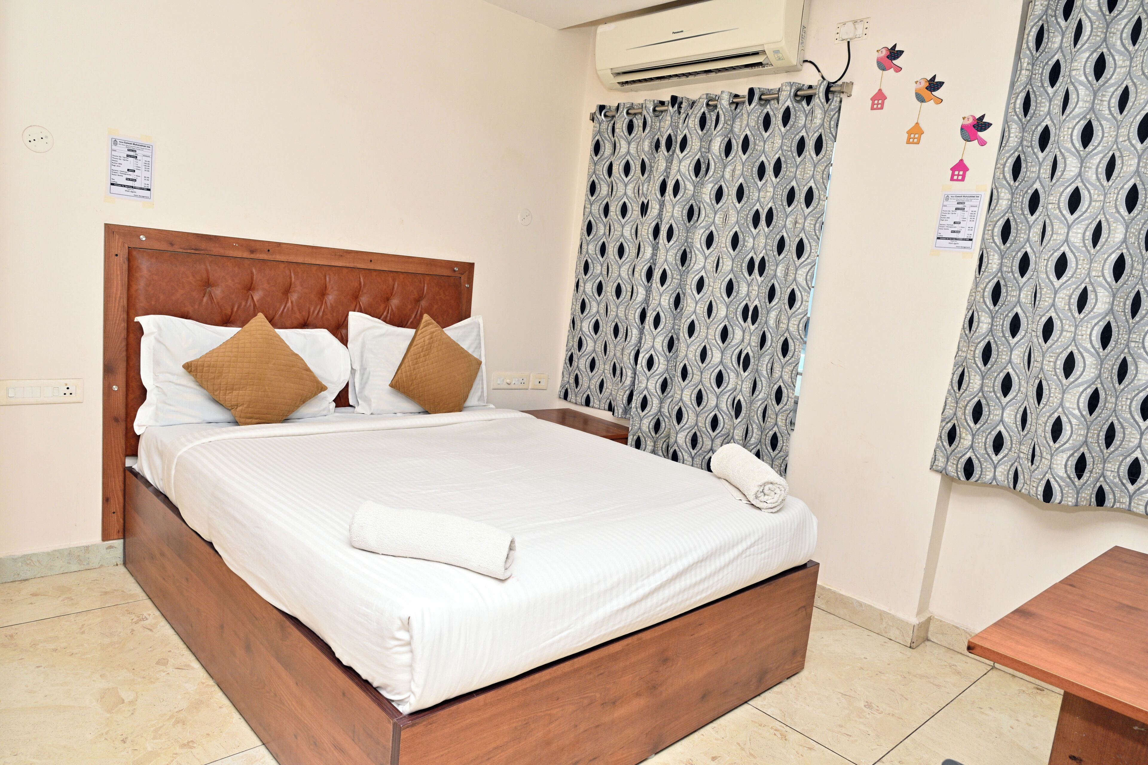 A neatly made bed with a wooden headboard, a white comforter, and two brown pillows.