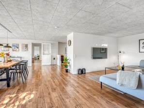 Ein großzügiger Wohnbereich mit Holzboden, einem Esstisch mit Stühlen, einer Couch und einem an der Wand befestigten Fernseher.