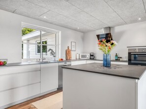 Eine moderne Küche mit einer großen Kochinsel, weißen Schränken und einem Bosch-Ofen.