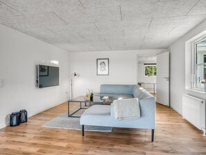 Un salon moderne avec un canapé gris, un téléviseur à écran plat et un tableau encadré accroché au mur.