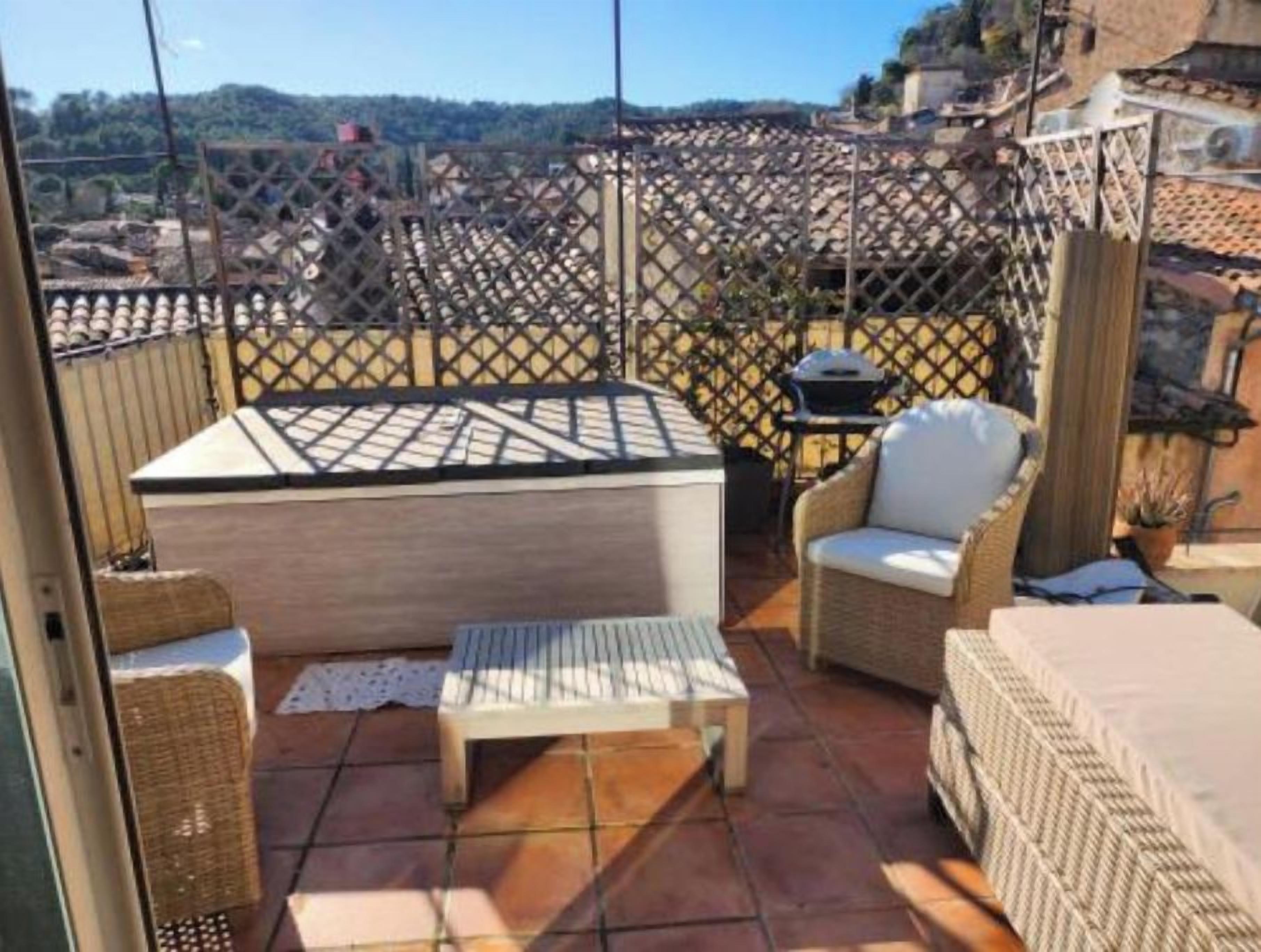 Una terrassa amb mobles de vimet, una taula i una barbacoa.