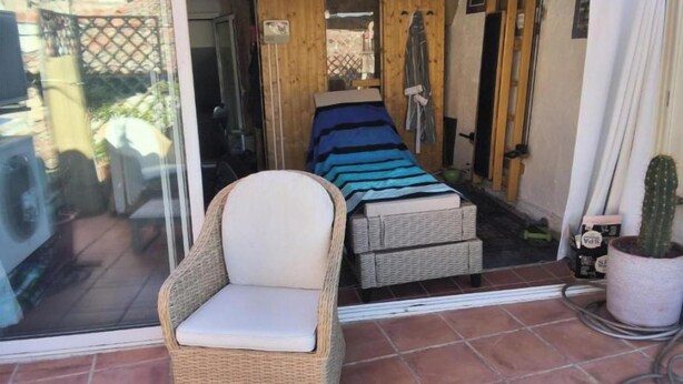 A room with a wicker chair, a bed with a striped bedspread, and a potted cactus. - The Boat on the Rooftops (Cotignac)