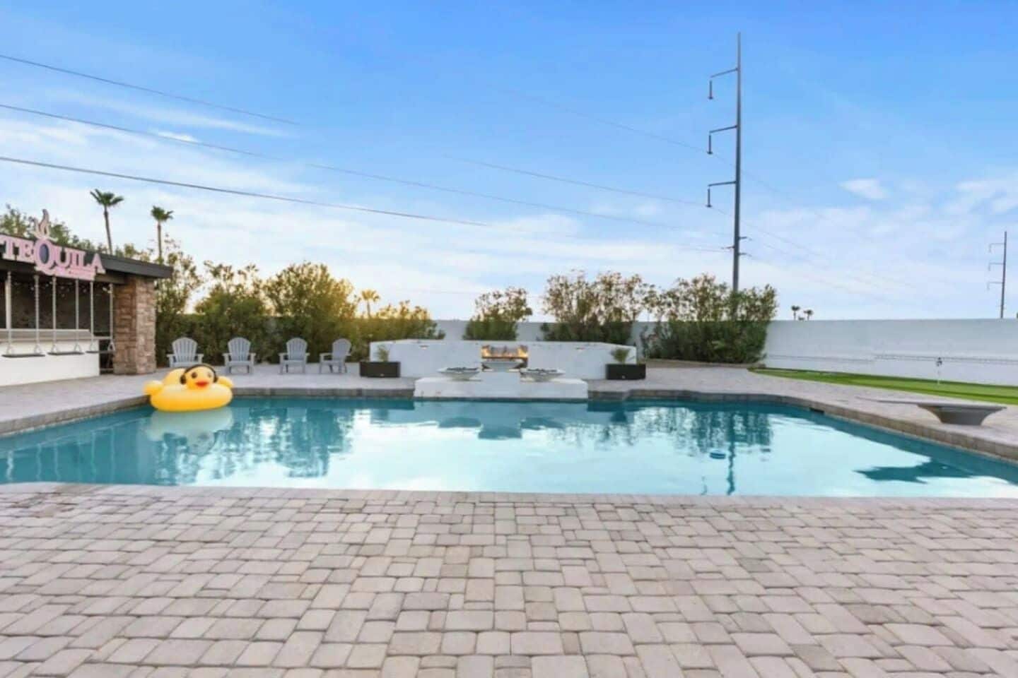 A swimming pool with a duck float, lounge chairs, and a bar area.