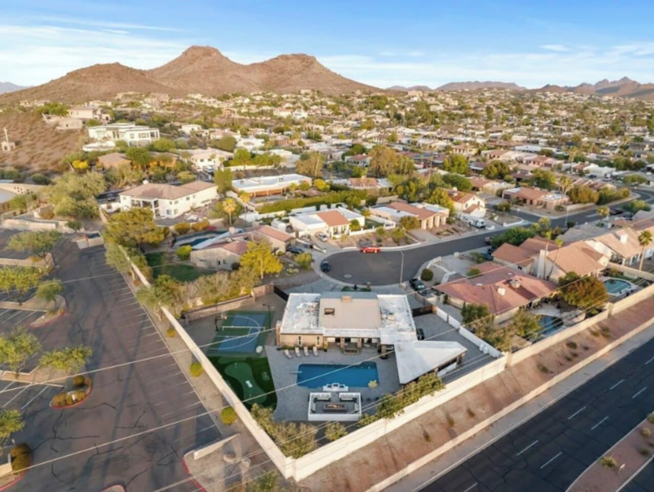 An aerial view of a residential area with houses, a swimming pool, and a basketball court.