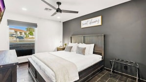 Un dormitorio con cama, ventilador de techo, ventana con vistas y un cartel en la pared.