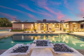 A pool area with lounge chairs and a stone fire feature.