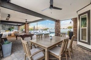 An outdoor patio with a pool table, seating, and a view of the water.