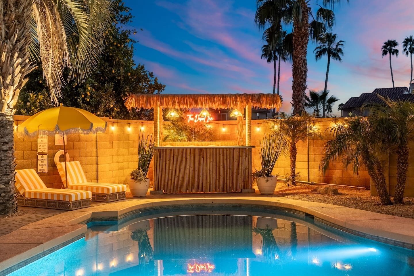 A poolside area with lounge chairs, a tiki bar, and a pool.