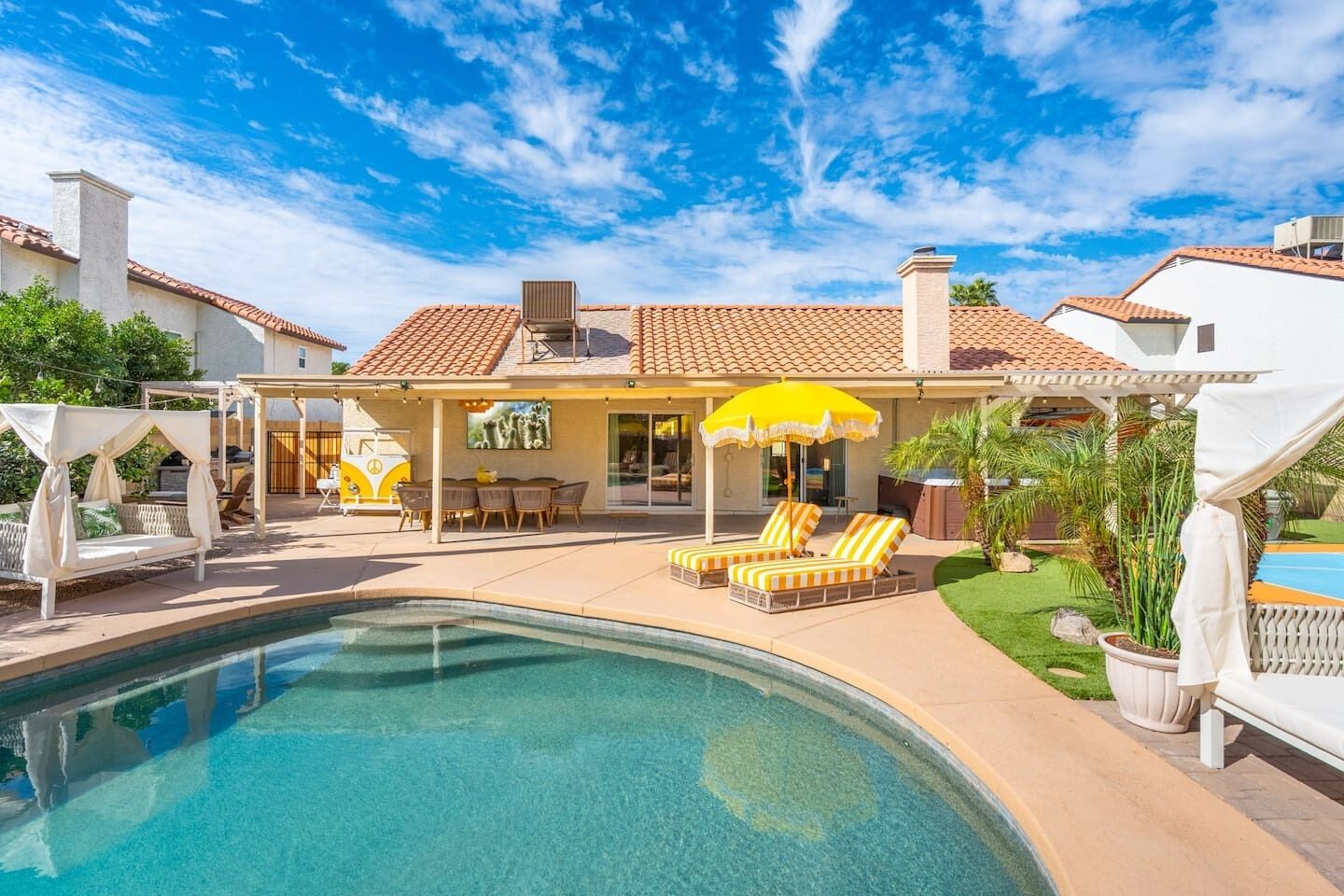 A backyard with a swimming pool, lounge chairs, and a covered patio area.