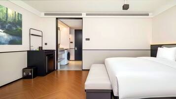 Una habitación de hotel moderna con una cama grande, un escritorio integrado, una lavadora y un espejo.