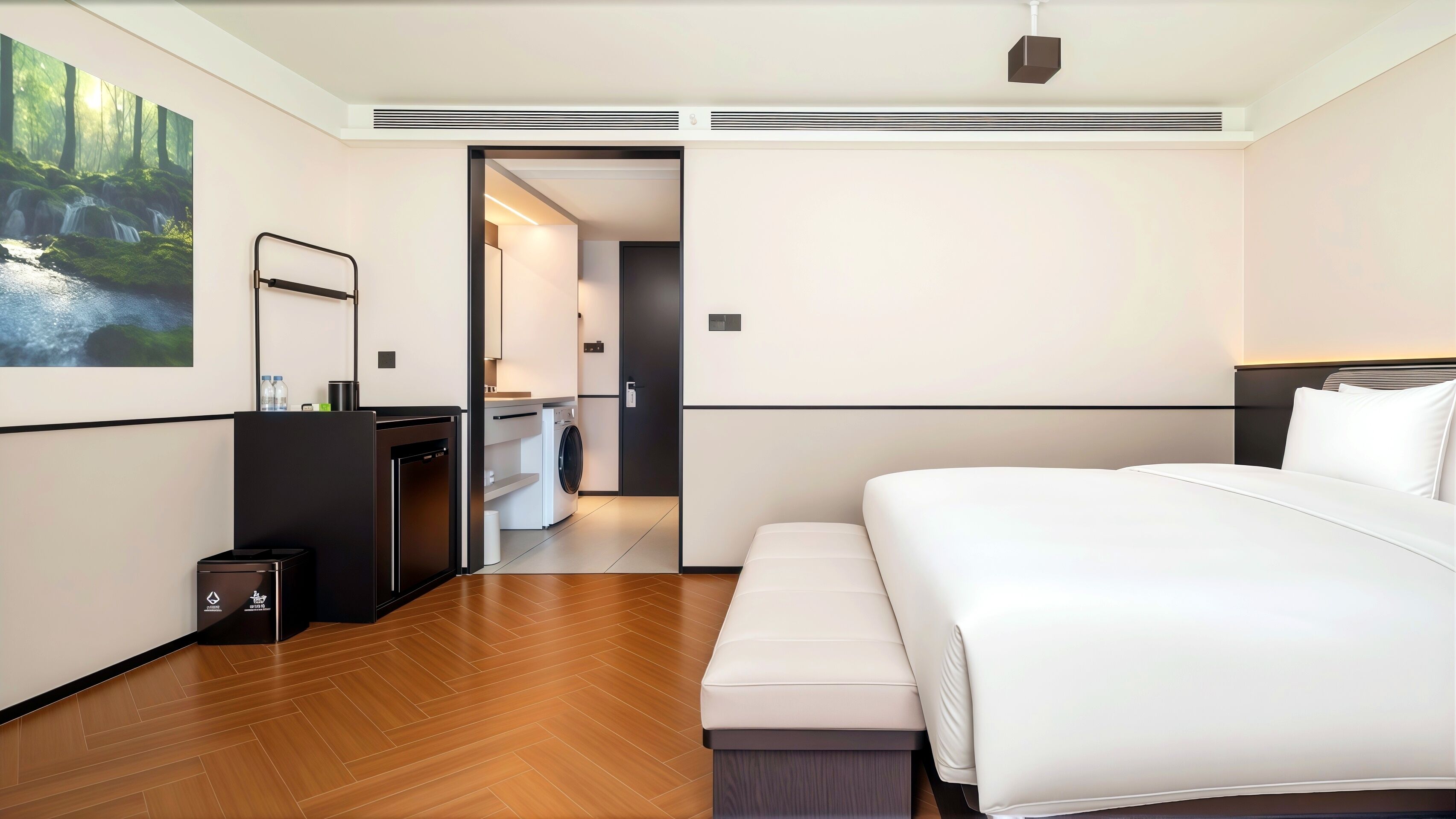Habitació d'hotel moderna amb un llit gran, una taula petita, una rentadora i un bany visible per una porta oberta.