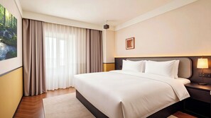 A hotel room with a large bed, a nightstand with a lamp, a painting on the wall, and a window with curtains. - Chengdu Sunshine Stay Hotel (Chengdu)