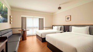 Habitación de hotel con dos camas, un sofá, una mesita y un cuadro en la pared.