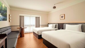 A hotel room with two beds, a sofa, a small table, and a painting on the wall. - Chengdu Sunshine Stay Hotel (Chengdu)
