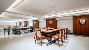 Una sala de conferencias moderna con una mesa grande, sillas y un proyector.