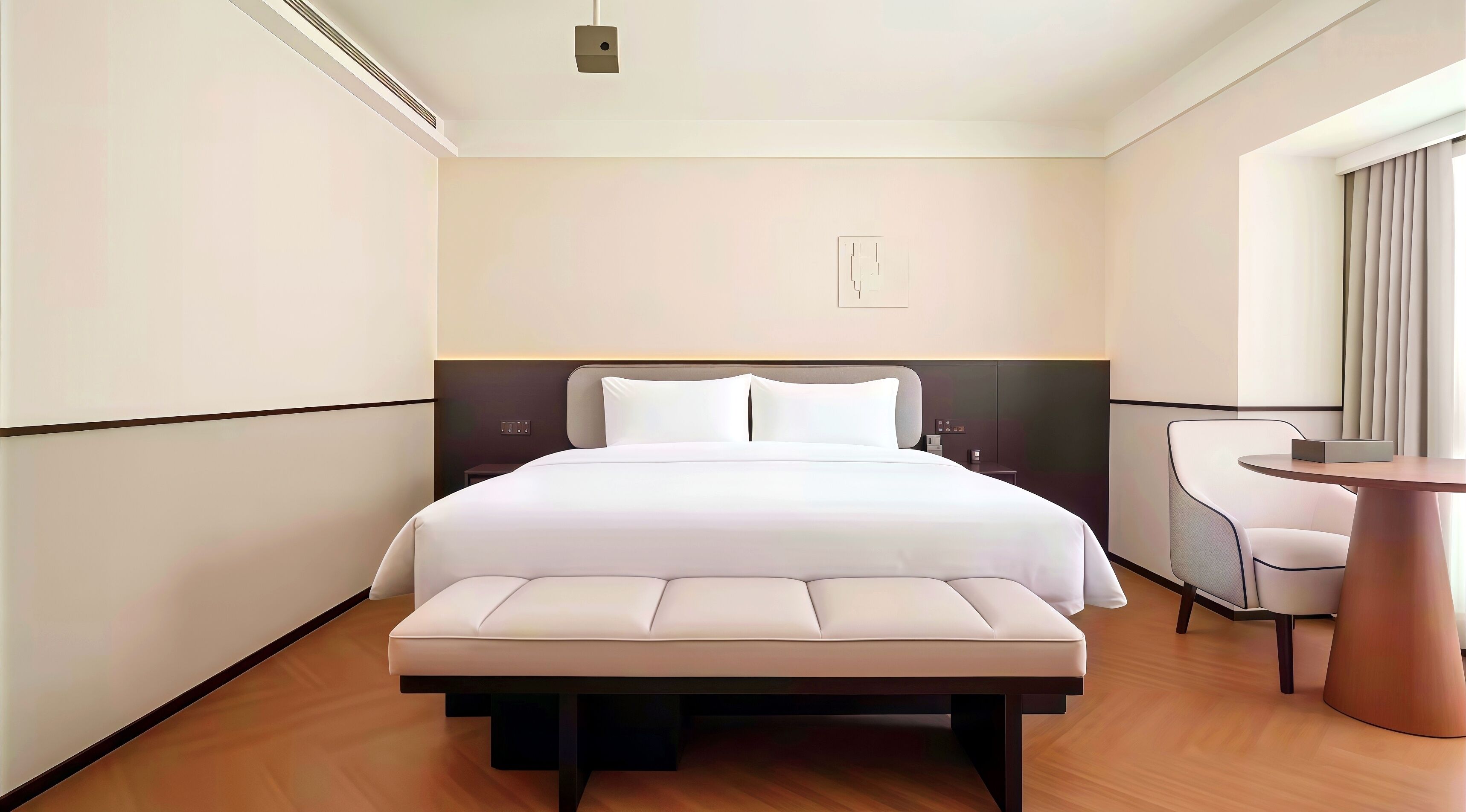 A hotel room with a bed, bedside table, chair, and a small round table.