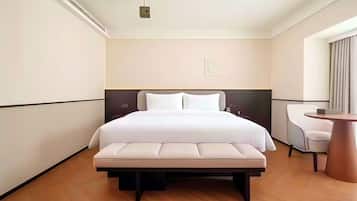 A hotel room with a bed, bedside table, chair, and a small round table.