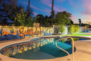 A swimming pool with a mural, surrounded by trees and a sunset sky. - Ultimate Backyard | Pool, Pickleball, and Golf! (Scottsdale)