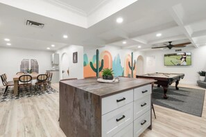 A spacious room with a pool table, dining area, and a large island with drawers. - Ultimate Backyard | Pool, Pickleball, and Golf! (Scottsdale)