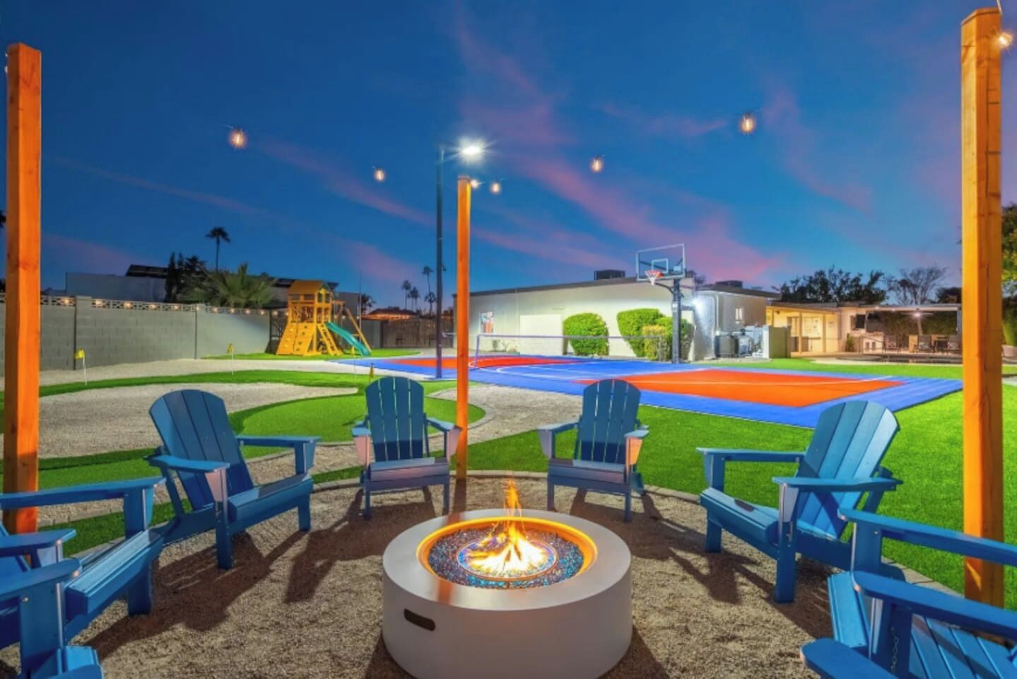 Una chimenea con sillas, una cancha de baloncesto y un parque infantil.