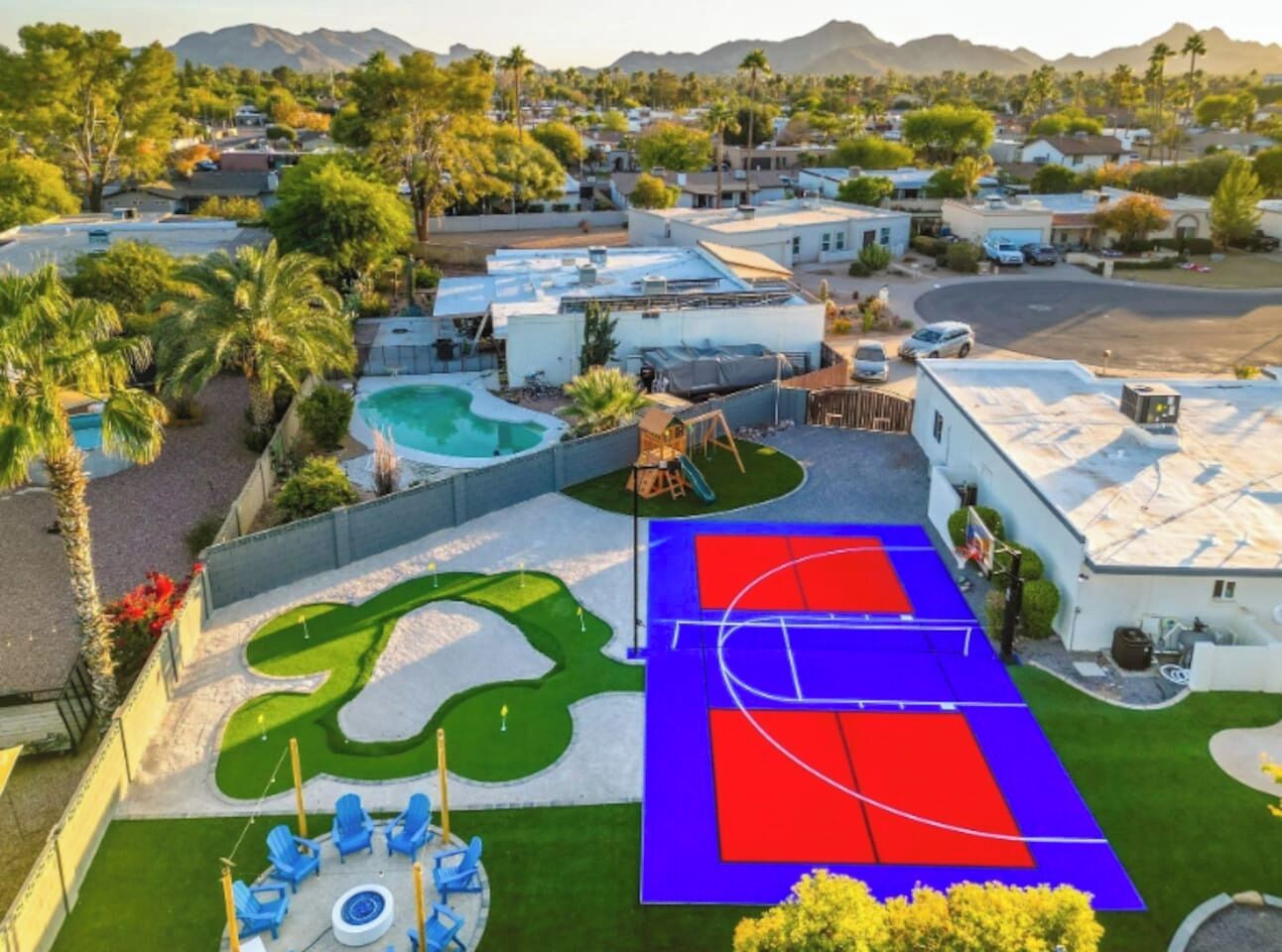 A residential area with a swimming pool, a basketball court, and a golf putting area.