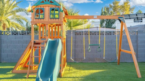 A playground with a slide, swing set, and climbing structure. - Ultimate Backyard | Pool, Pickleball, and Golf! (Scottsdale)