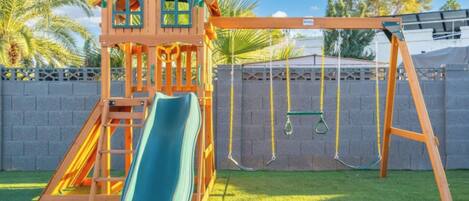 A playground with a slide, swing set, and climbing structure.