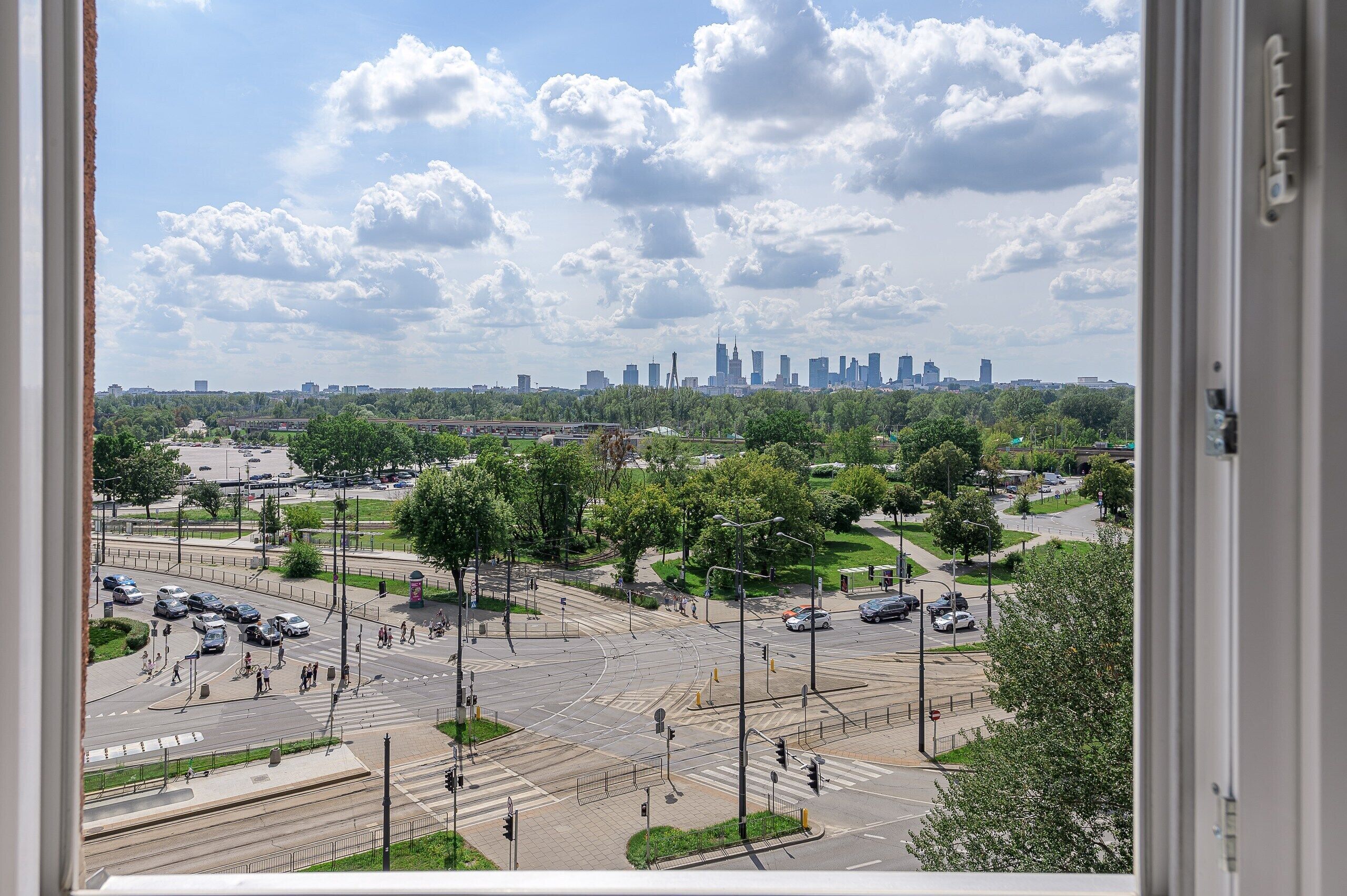 Une vue urbaine caractérisée par une silhouette de bâtiments imposante, un carrefour animé et une végétation luxuriante environnante.