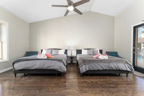 Een slaapkamer met twee bedden, een plafondventilator en een deur met uitzicht.