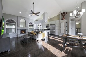 Un amplio salón con chimenea, una mesa de comedor y una cocina equipada con electrodomésticos modernos.
