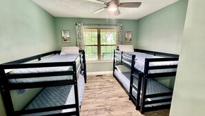 Ein Zimmer mit Etagenbetten, einem Deckenventilator und einem Fenster mit Vorhängen.